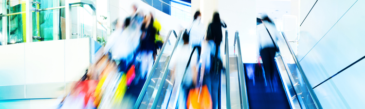 people rushing in escalators at a modern shopping mall.